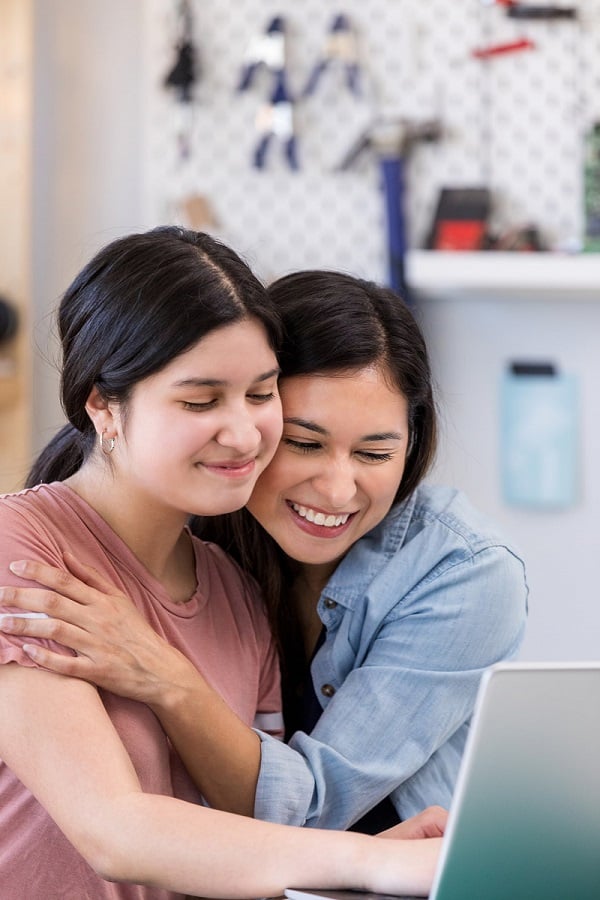 Mother and Daughter Looking at Laptop and Smiling